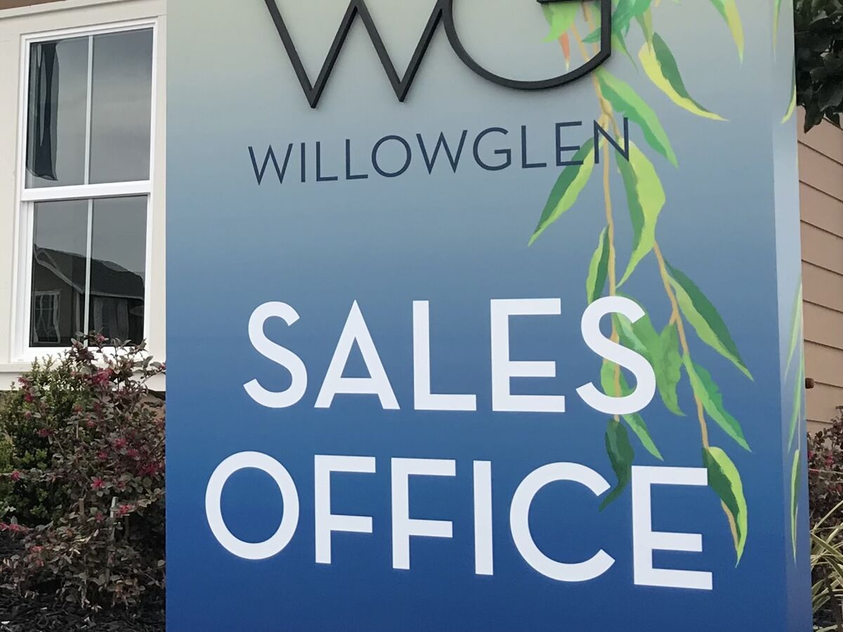 Freestanding panel sign with dimensional WG letters over a painted willow-leaf illustration reading WillowGlen Sales Office