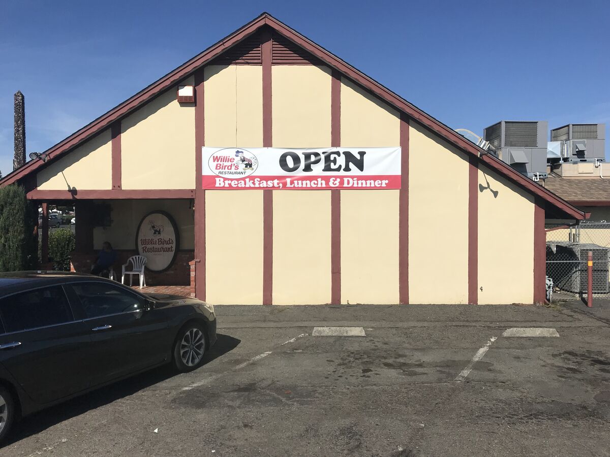 Large banner mounted high on a restaurant gable end reading OPEN, Breakfast, Lunch and Dinner